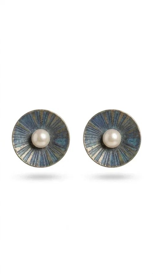 , These handmade stud earrings with pearls in deep blue color are an elegant choice for every woman seeking jewelry with character and quality. Designed by Greek Jewelry Designer Aikaterini Chalkiadaki, these earrings combine the traditional art of enamel with the timeless beauty of the pearl, creating a result that truly stands out.

The circular brass shape with a relief surface in a radiant sunburst pattern gives the piece an open, flower-like character. The blue-toned enamel evenly covers the base, while at the center a white pearl stands out, adding finesse and contrast. Their stud design makes them ideal for everyday wear, as well as for formal occasions.

Wear them paired with linen or neutral outfits to highlight their color palette, or choose them as a statement piece for weddings, christenings, and every special moment.