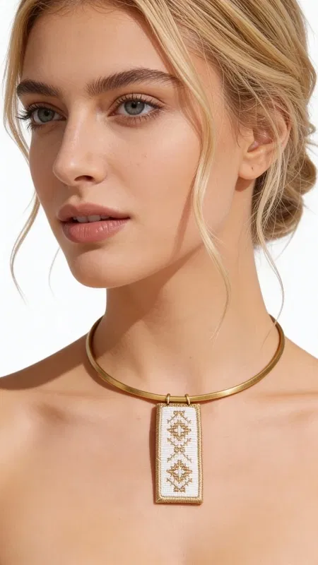 , This striking statement pendant necklace showcases the perfect marriage of traditional Greek embroidery and contemporary jewelry design. The centerpiece features a pristine white textile canvas adorned with intricate geometric diamond motifs, meticulously hand-stitched with luminous gold thread that catches and reflects light beautifully.
The embroidered textile is elegantly framed within a sleek brass rectangular setting, creating a sophisticated contrast between the soft, nostalgic appeal of folk art and the strong architectural lines of modern metalwork. The pendant hangs gracefully from a polished brass collar necklace that sits beautifully at the collarbone, ensuring the embroidered artwork takes center stage.
This piece celebrates the rich heritage of Greek folk art tradition, reimagining classic kentima (embroidery) techniques for the contemporary woman who appreciates both cultural depth and modern sophistication.
The collar-style design makes this necklace incredibly versatile – perfect for elevating a simple blouse for evening occasions or adding artistic flair to your everyday wardrobe. Its statement presence commands attention while remaining elegantly wearable.
Care Instructions:
Clean brass gently with soft cloth. Protect embroidered textile from moisture and store flat when not worn.